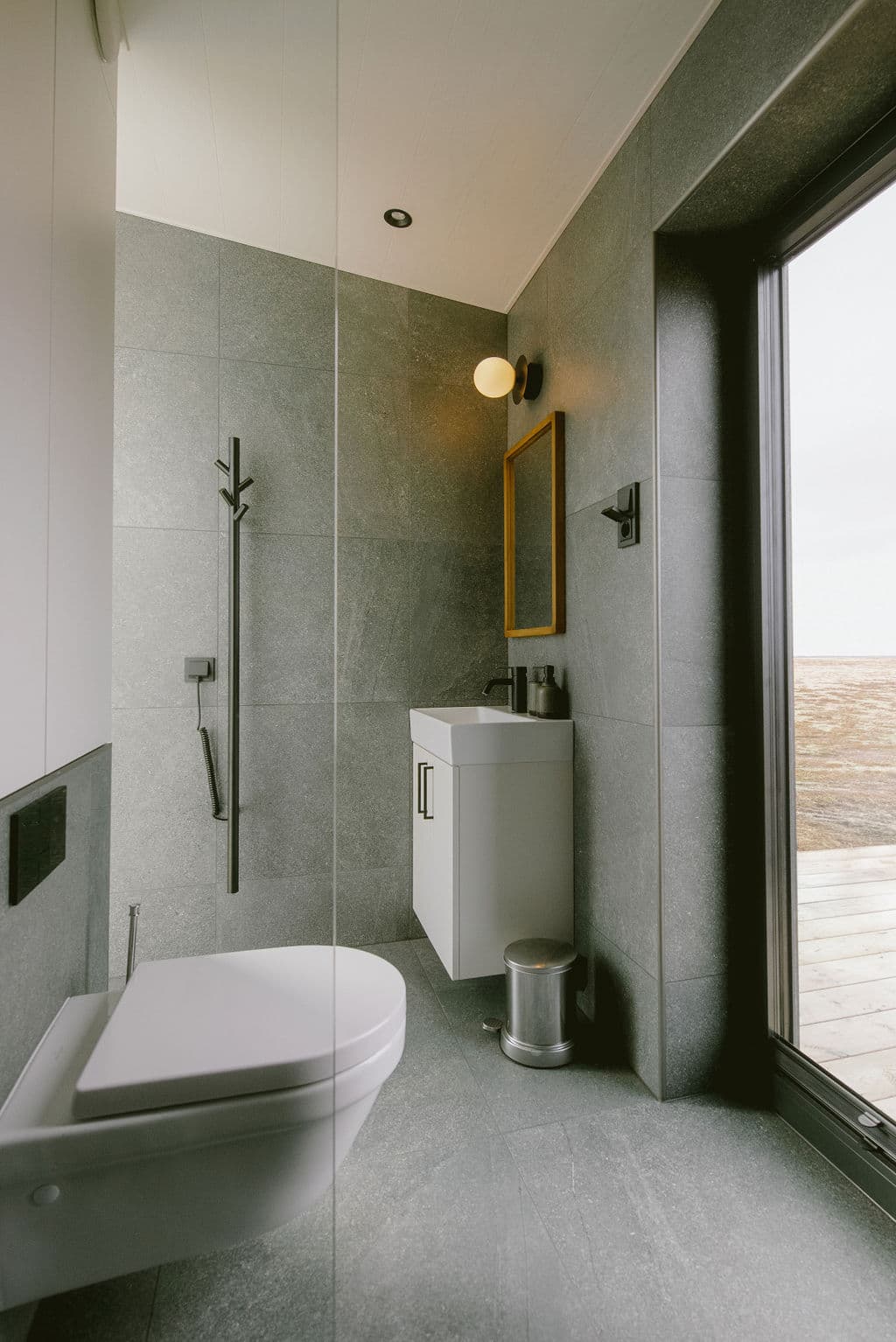 Minimalist bathroom with wall-mounted toilet and large window at Rafter Seljalandsfoss Georg, Hvolsvöllur