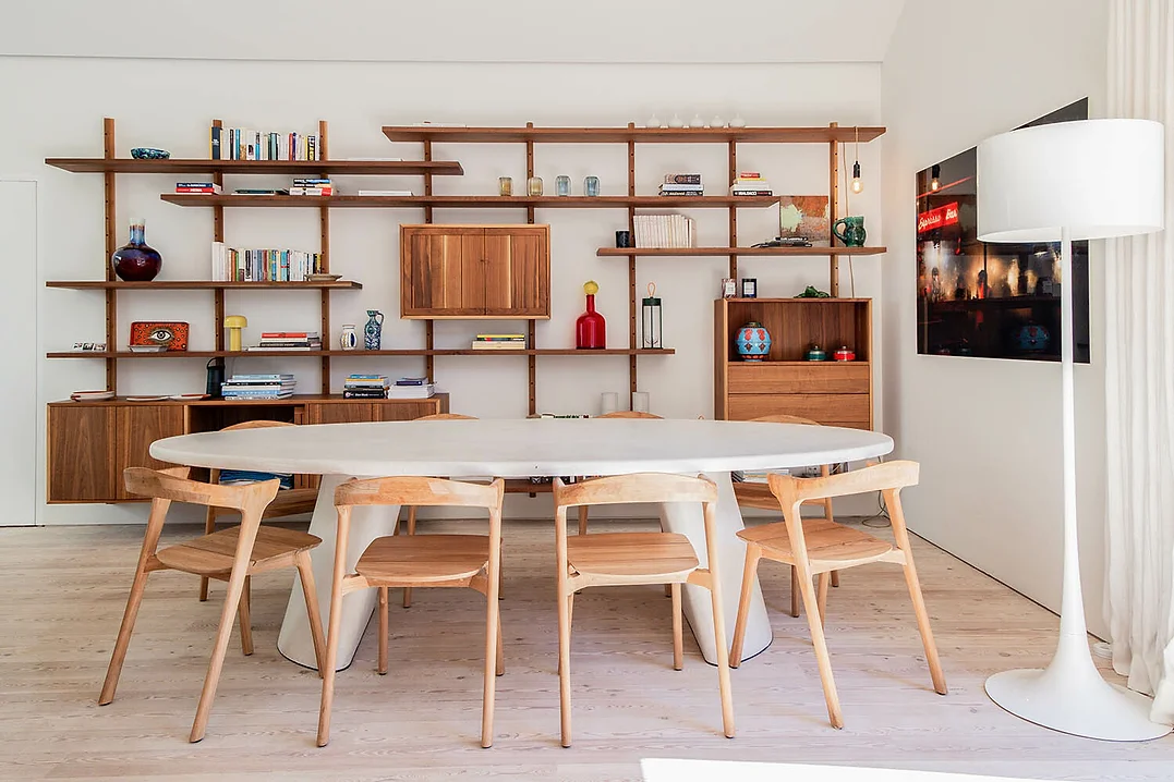 Dining area with oval table, wooden chairs, and wall shelving at Rafter Melides Atlantica in Melides, Portugal