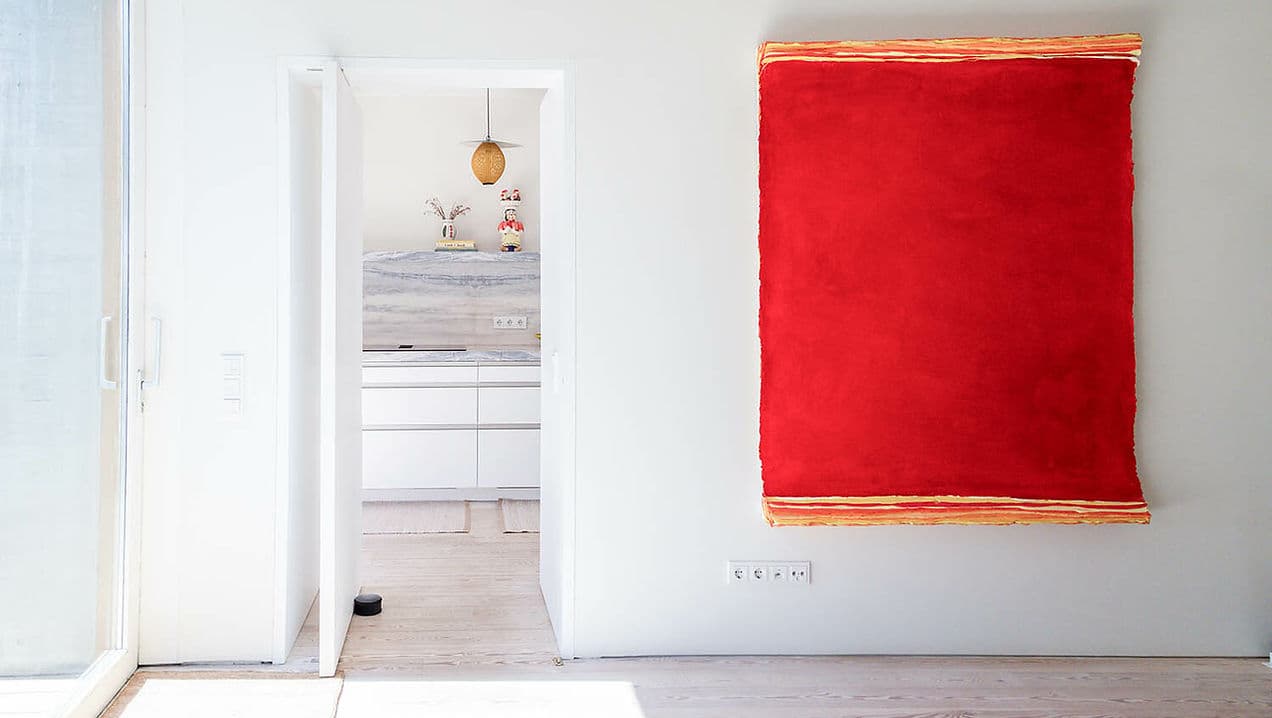 Minimalist living space with modern kitchen and large abstract red wall art at Rafter Melides Atlantica, Melides, Portugal