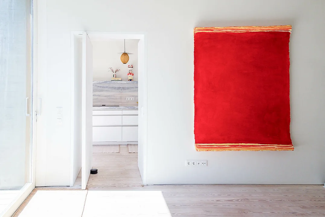 Minimalist living space with modern kitchen and large abstract red wall art at Rafter Melides Atlantica, Melides, Portugal