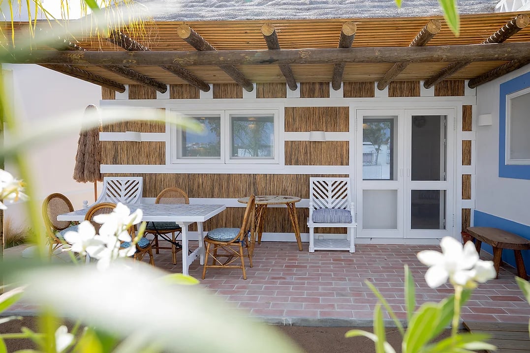 Outdoor dining patio with wooden pergola and rattan seating at Casa Mounette Portugal
