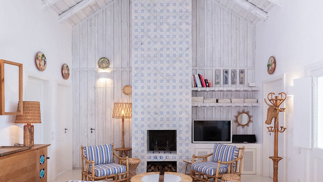 Living room with striped armchairs and tiled fireplace at Casa Mounette in Portugal