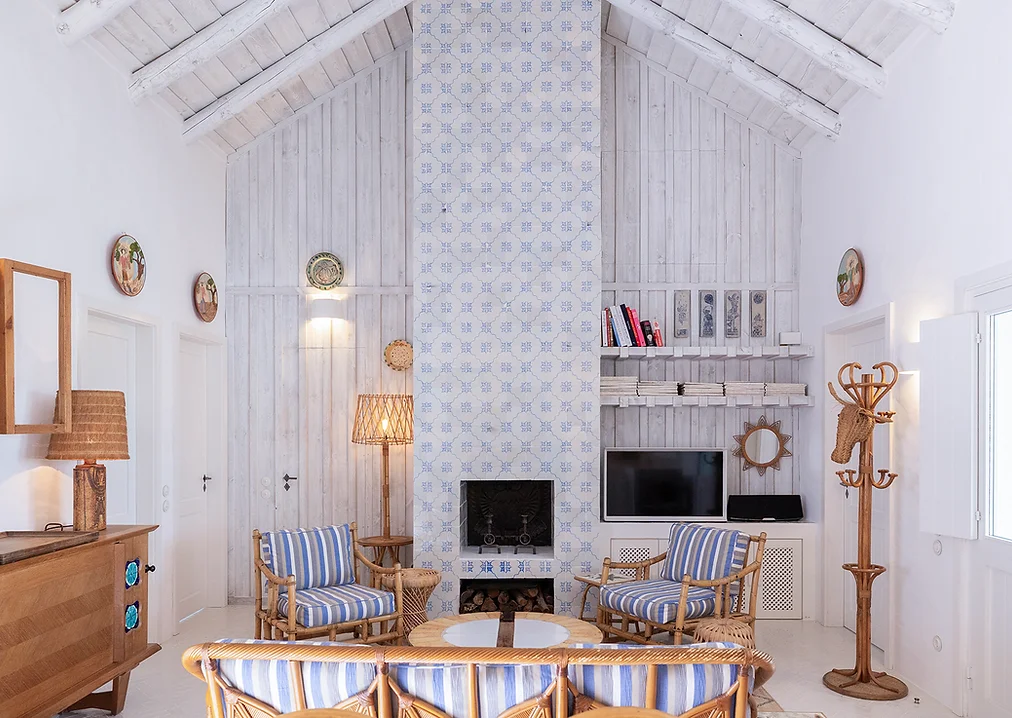 Living room with striped armchairs and tiled fireplace at Casa Mounette in Portugal