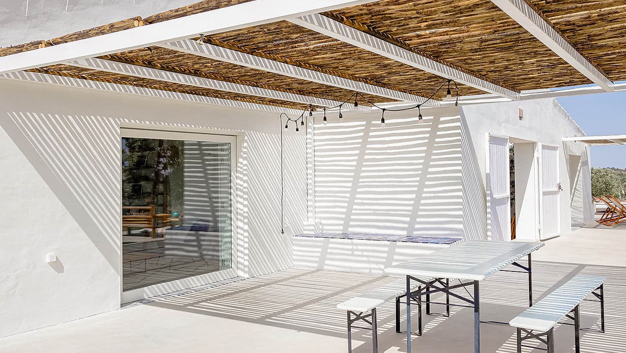 Outdoor shaded dining area with bench seating at Casa Acima in Santiago do Cacém, Portugal