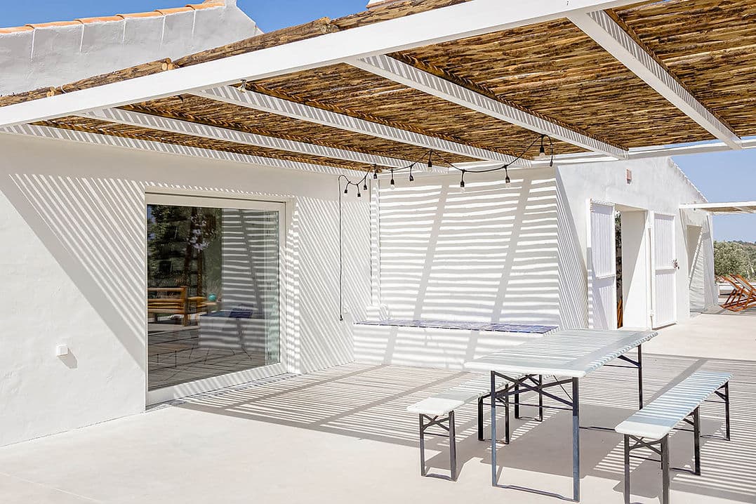 Outdoor shaded dining area with bench seating at Casa Acima in Santiago do Cacém, Portugal
