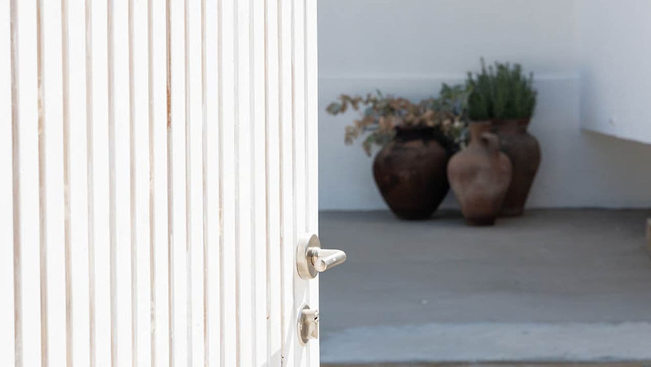 White wooden door partially open with terracotta pots inside Rafter Carvalhal Bicas in Carvalhal, Portugal
