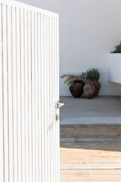 White wooden door partially open with terracotta pots inside Rafter Carvalhal Bicas in Carvalhal, Portugal
