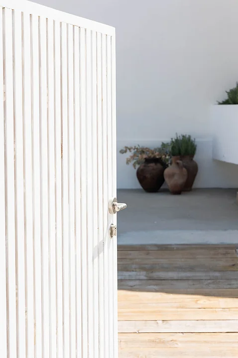White wooden door partially open with terracotta pots inside Rafter Carvalhal Bicas in Carvalhal, Portugal