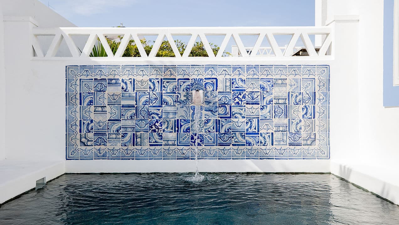 Outdoor pool with decorative blue tile fountain wall at Casa Mounette in Portugal