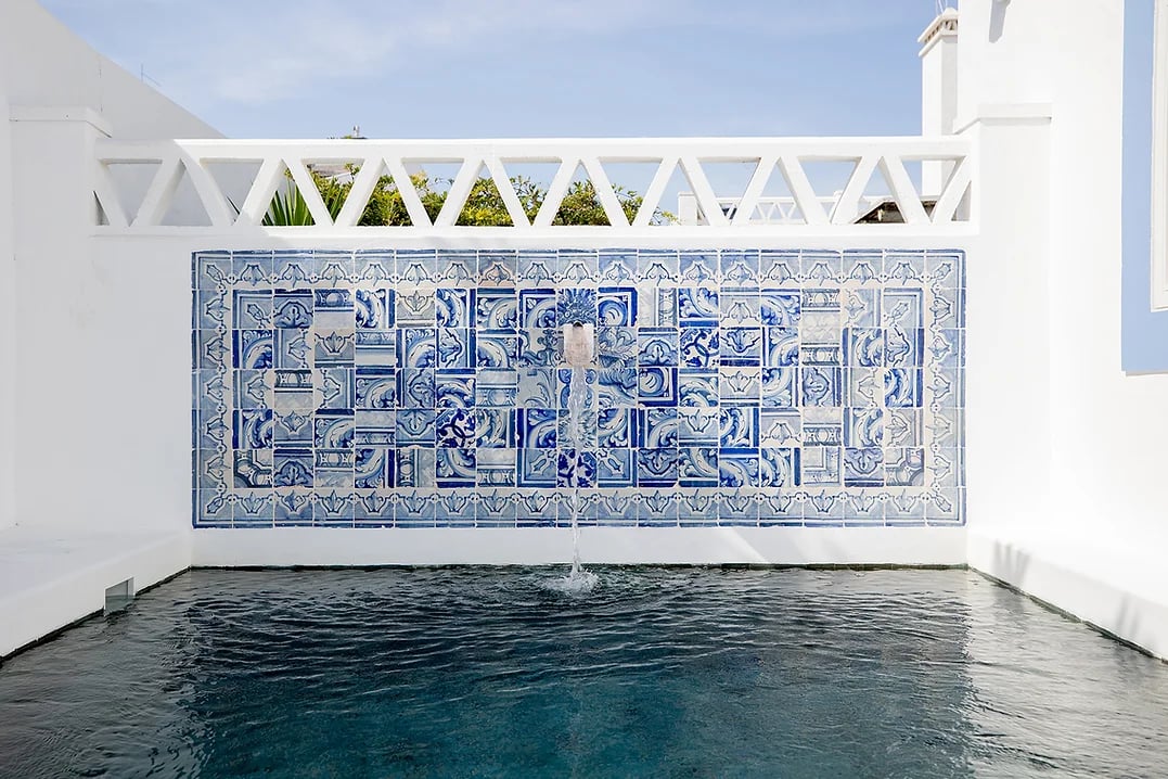 Outdoor pool with decorative blue tile fountain wall at Casa Mounette in Portugal