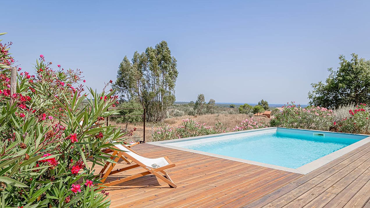 Outdoor swimming pool with wooden deck and countryside views at Casa Acima in Santiago do Cacém, Portugal