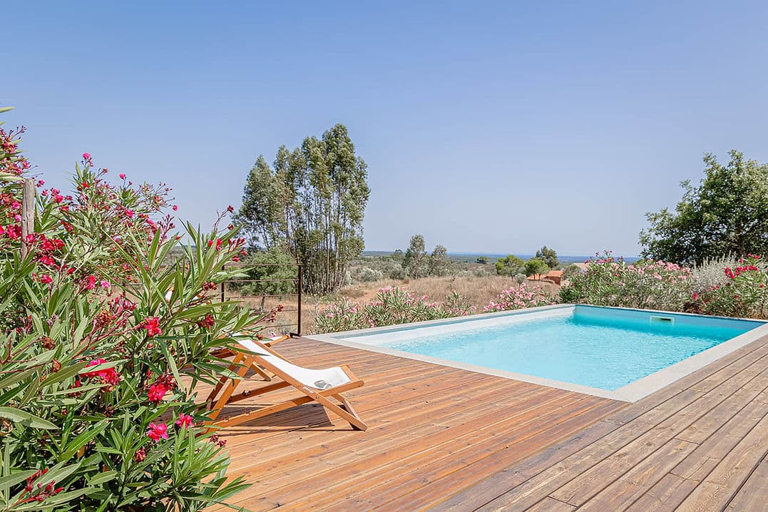 Outdoor swimming pool with wooden deck and countryside views at Casa Acima in Santiago do Cacém, Portugal
