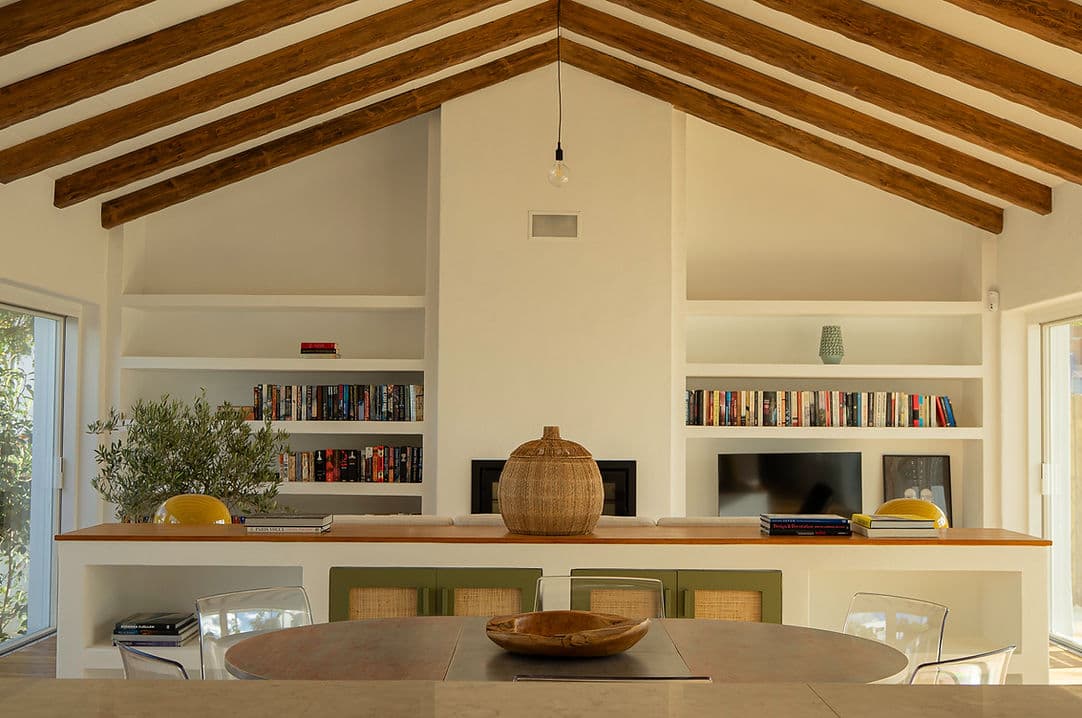 Living room with vaulted wood beam ceiling and built-in bookshelf at Rafter Melides Oliveiras in Melides, Portugal