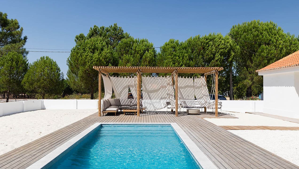 Outdoor pool and shaded seating area with curtains at Rafter Carvalhal Bicas in Carvalhal, Portugal