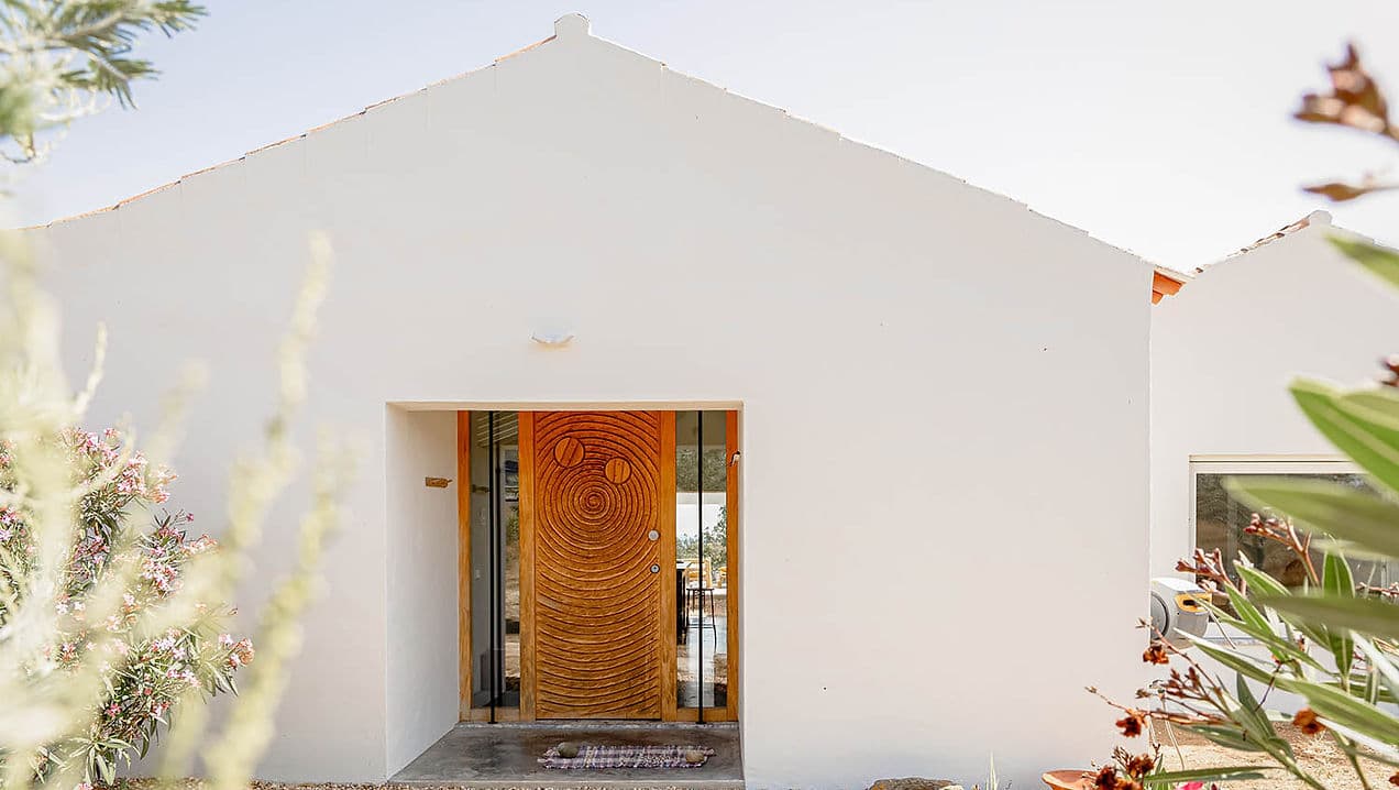White facade with artistic wooden front door at Casa Acima, Santiago do Cacém, Portugal vacation rental