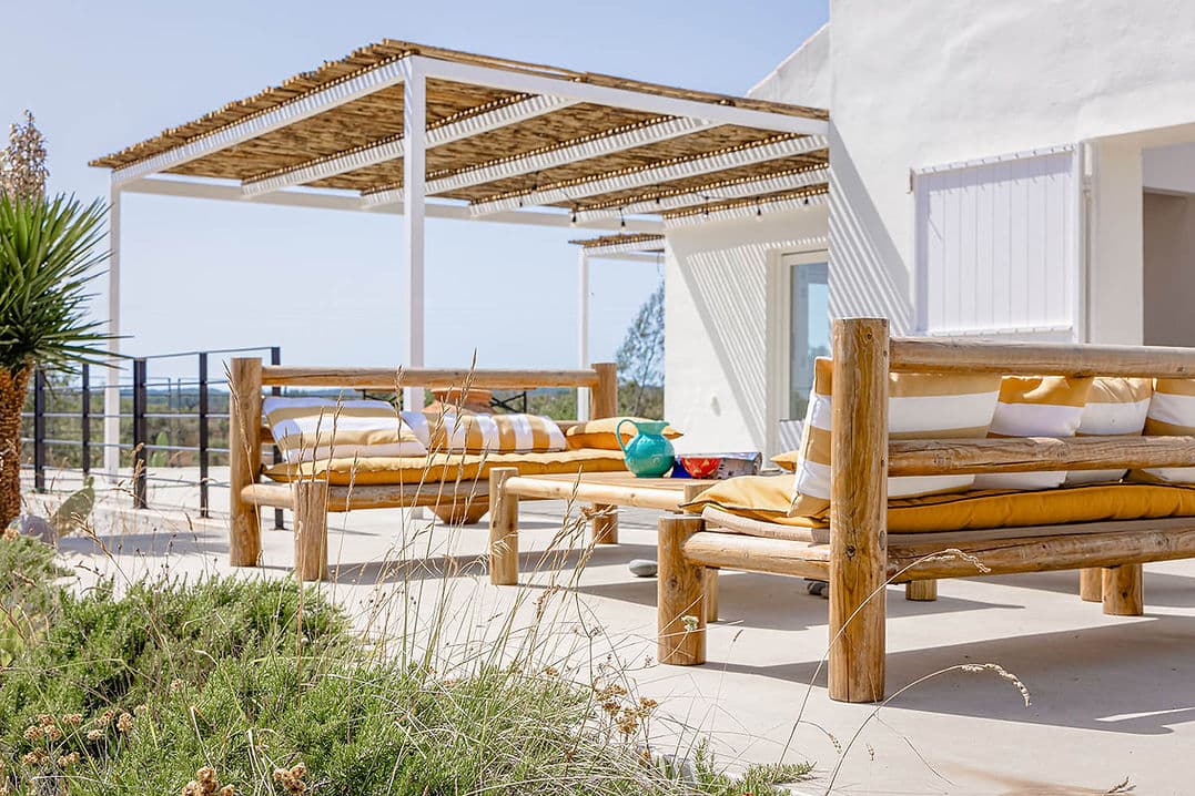 Outdoor lounge area with wooden furniture and shaded pergola at Casa Acima in Santiago do Cacém, Portugal