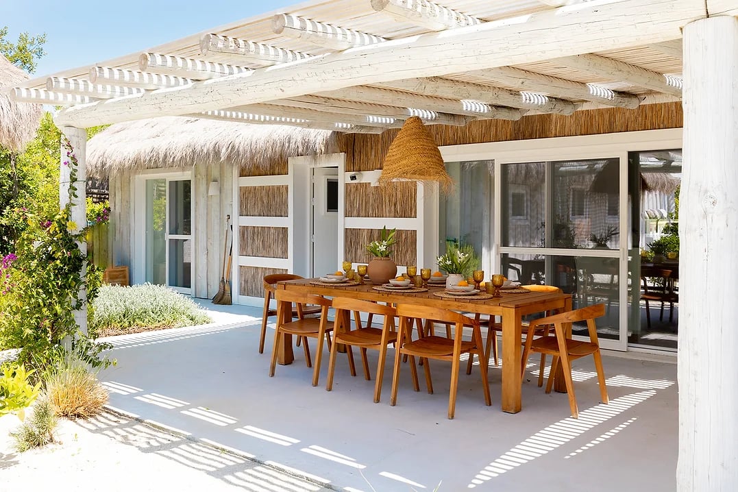 Outdoor dining area with wooden table and chairs under shaded pergola at Rafter Comporta Celeste in Comporta, Portugal