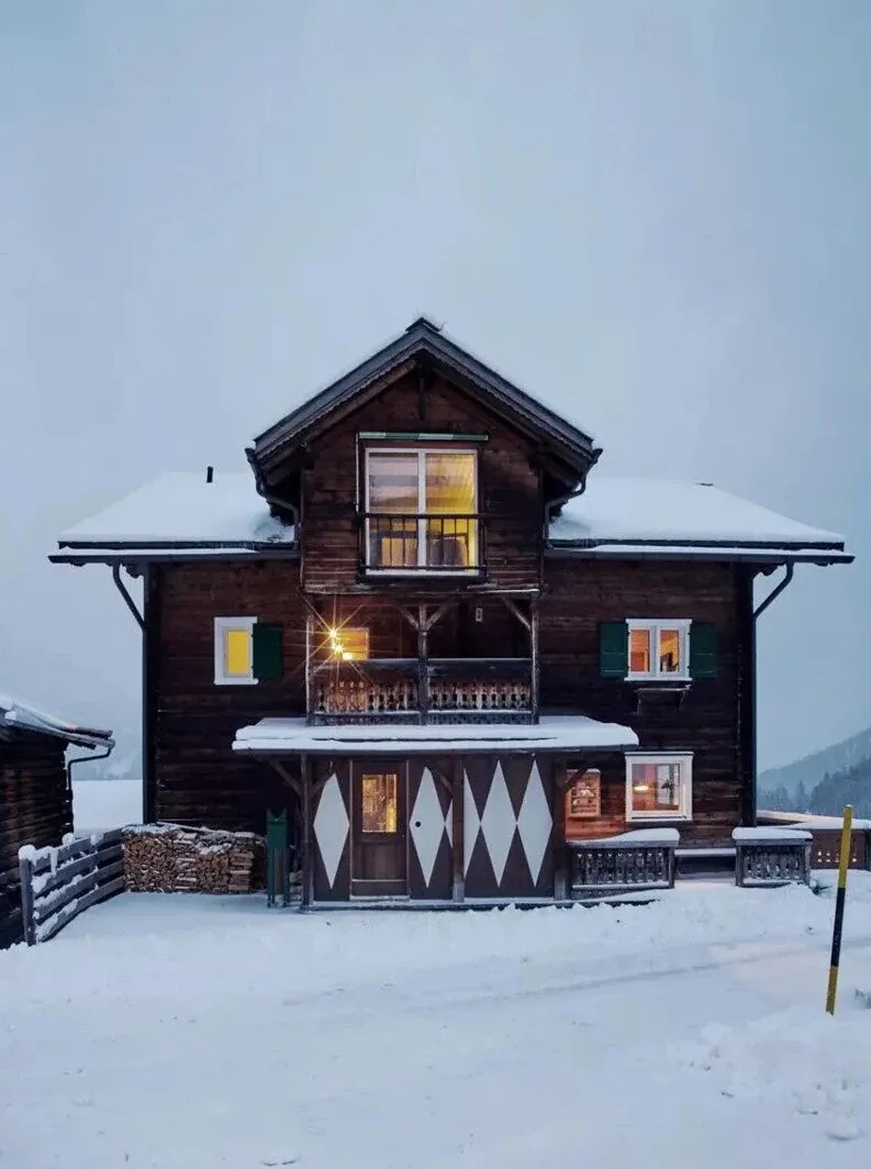 Rustic wooden chalet exterior at Rafter Tschiertschen in snowy Tschiertschen, Switzerland with balcony view