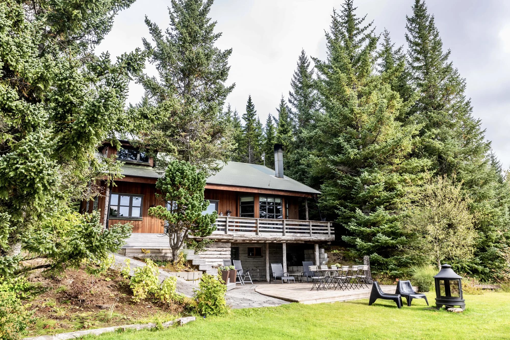 Wooden cabin exterior at Rafter Aslundur in Iceland with forest surroundings and outdoor seating area