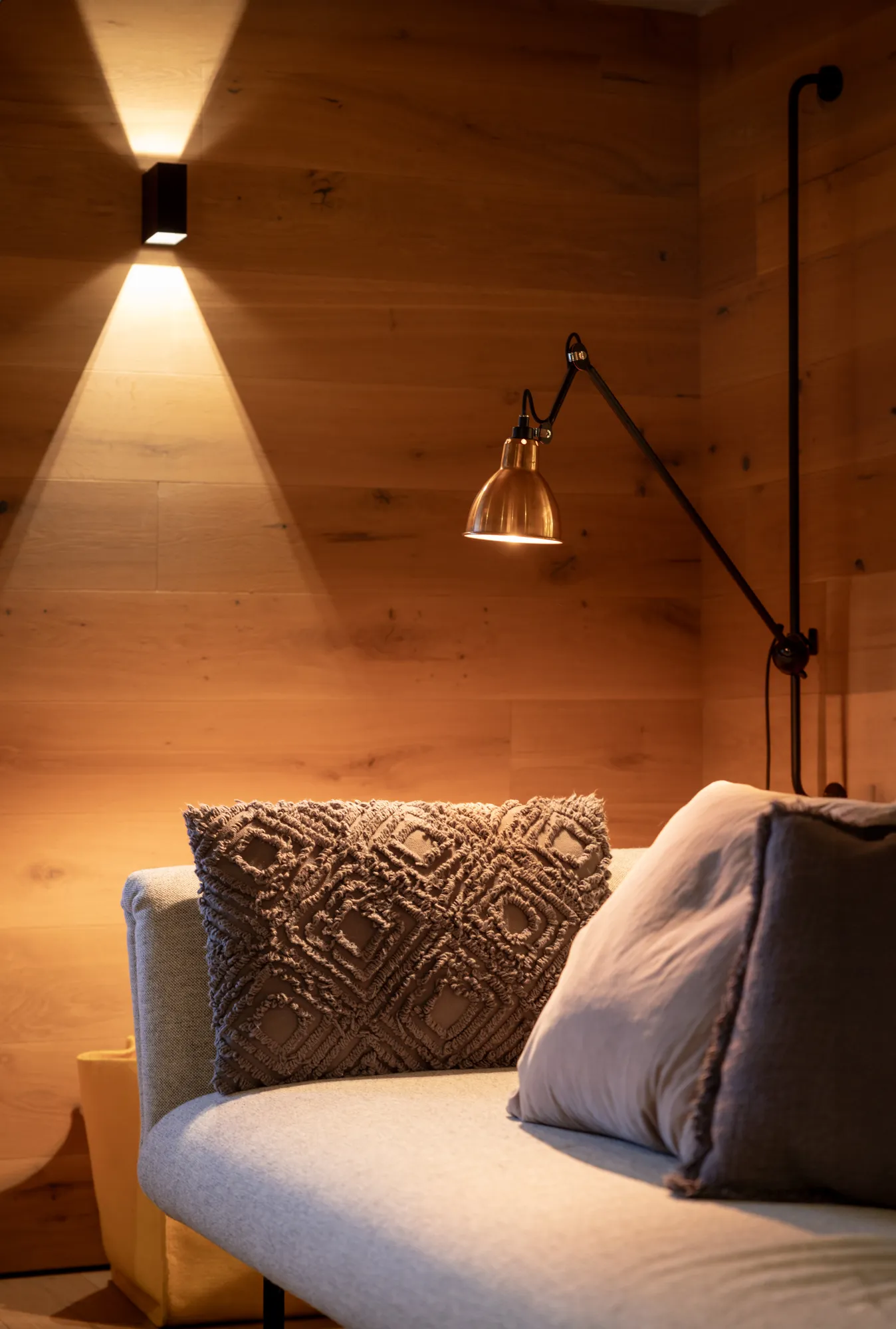 Cozy seating area with textured cushions and wall-mounted reading lamp at Rafter Bramberg, Bramberg am Wildkogel