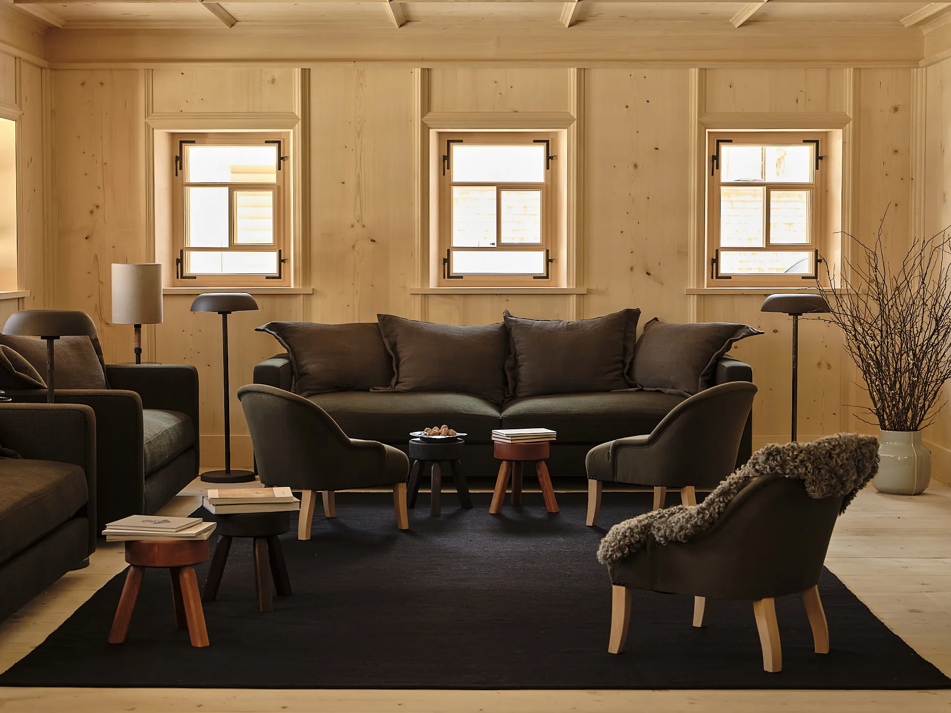 Living room with dark sofas and armchairs on black rug at Rafter Lech Zug in Lech, Austria
