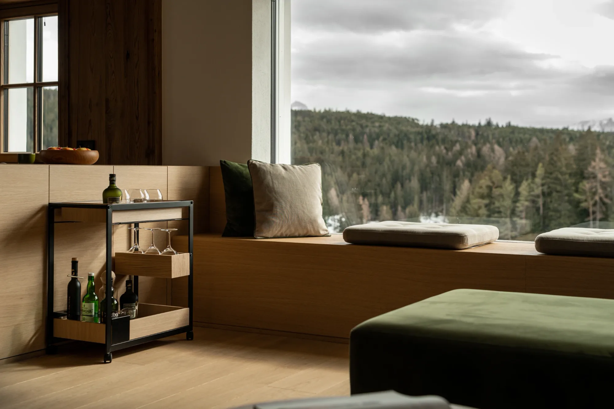 Seating area with cushions and forest view through large window at Rafter Bolzano Oberinn in Italy