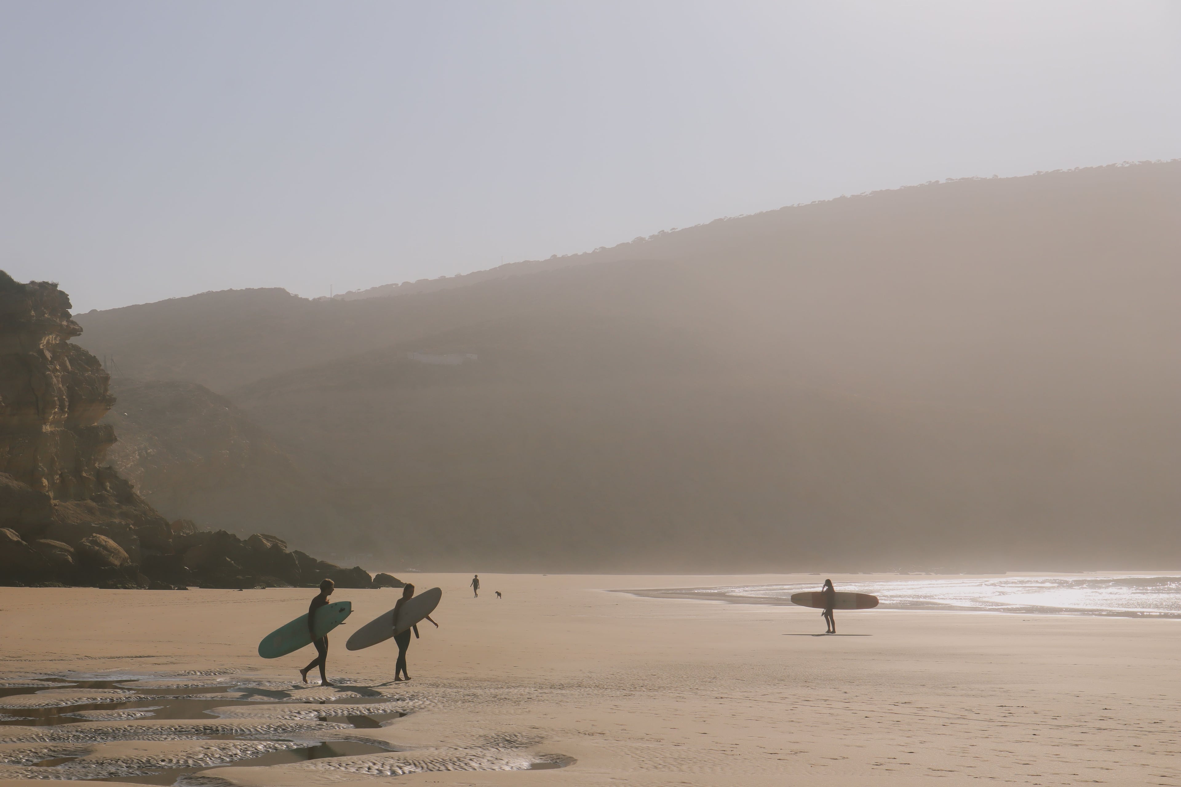 Surfers stamdomg pm a beach with glaring sun