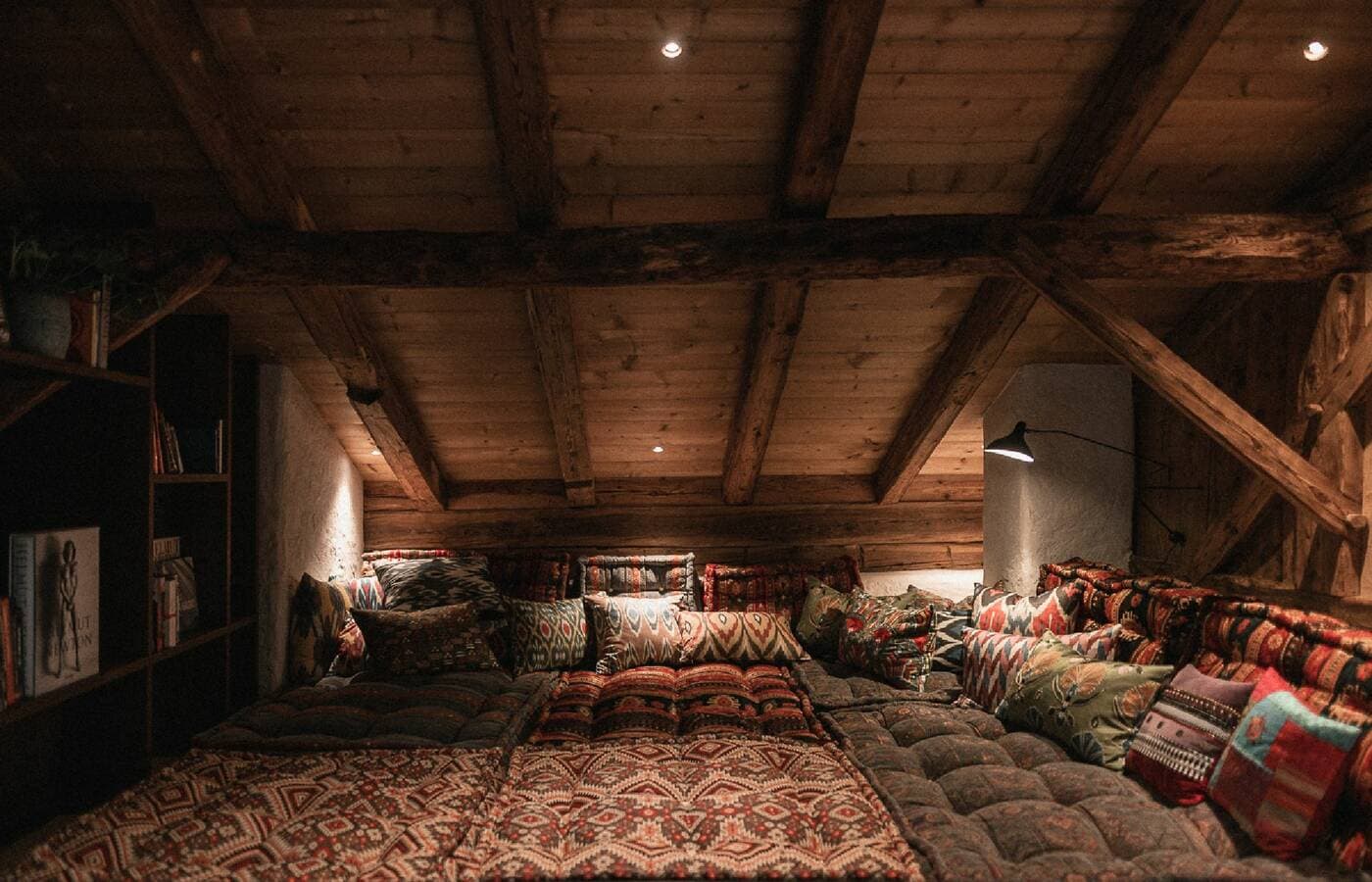 Cozy attic lounge with patterned cushions and wooden beams at Rafter Villanders in Villanders, Italy